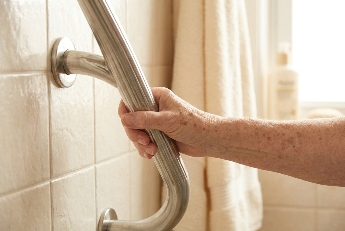 Hand hält Edelstahl-Haltegriff neben der Dusche